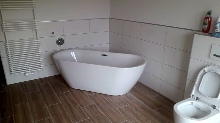 Freistehende Badewanne auf Bodenfliesen in Holzoptik
