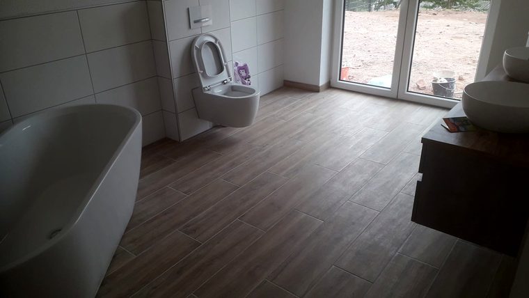 Fertiges Bad mit Wanne, Wand-WC und Holzoptik am Boden