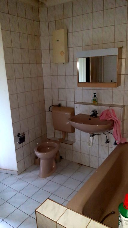 Altes Bad mit Spiegelschrank und kleinformatigen Wandfliesen