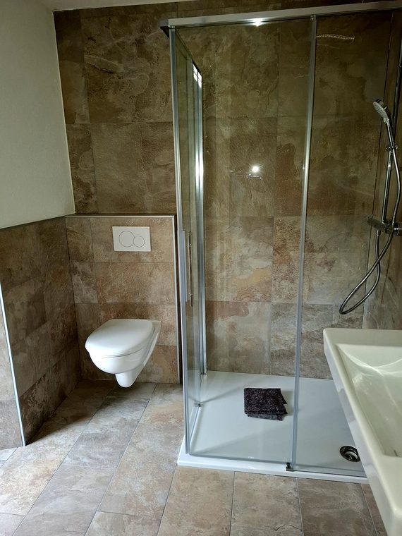 Neues Bad mit Duschkabine, Wand-WC und Fliesen in Natursteinoptik