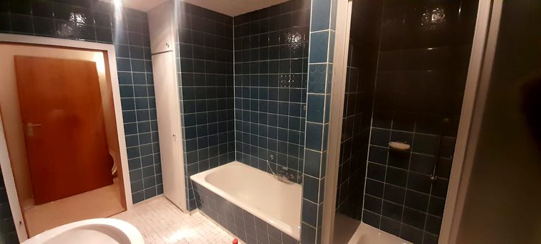 Blau gefliestes Bad mit Wanne und Duschkabine vor dem Rückbau