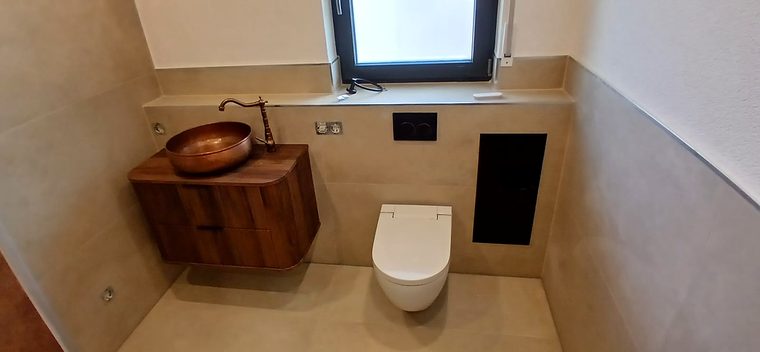 Fertiges Gäste-WC mit Kupferwaschbecken, Wand-WC und Großformatfliesen
