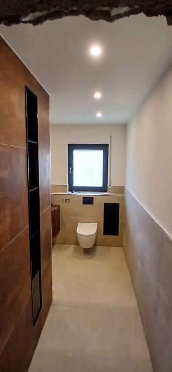 Fertiges Bad mit Fliesen in Rostoptik, schwarzer Nische und Wand-WC