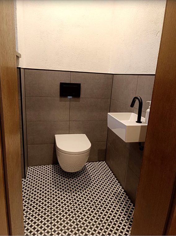 Fertiges Gästebad mit Wand-WC, Handwaschbecken und Musterfliesen
