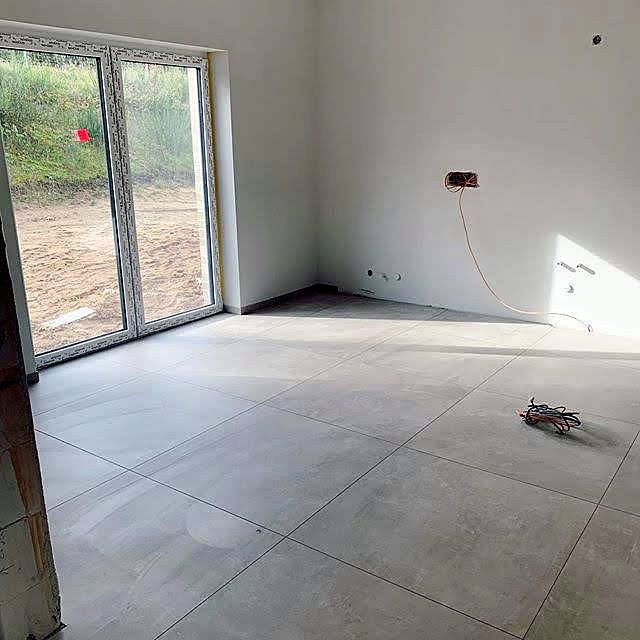 Wohnraum mit großformatigen Bodenfliesen und Terrassentür