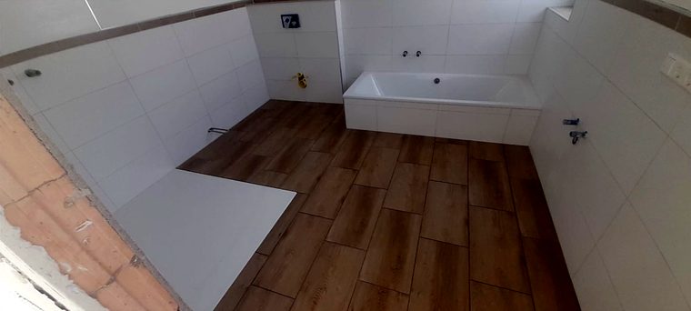 Gefliestes Bad mit Wanne und Bodenfliesen in Holzoptik